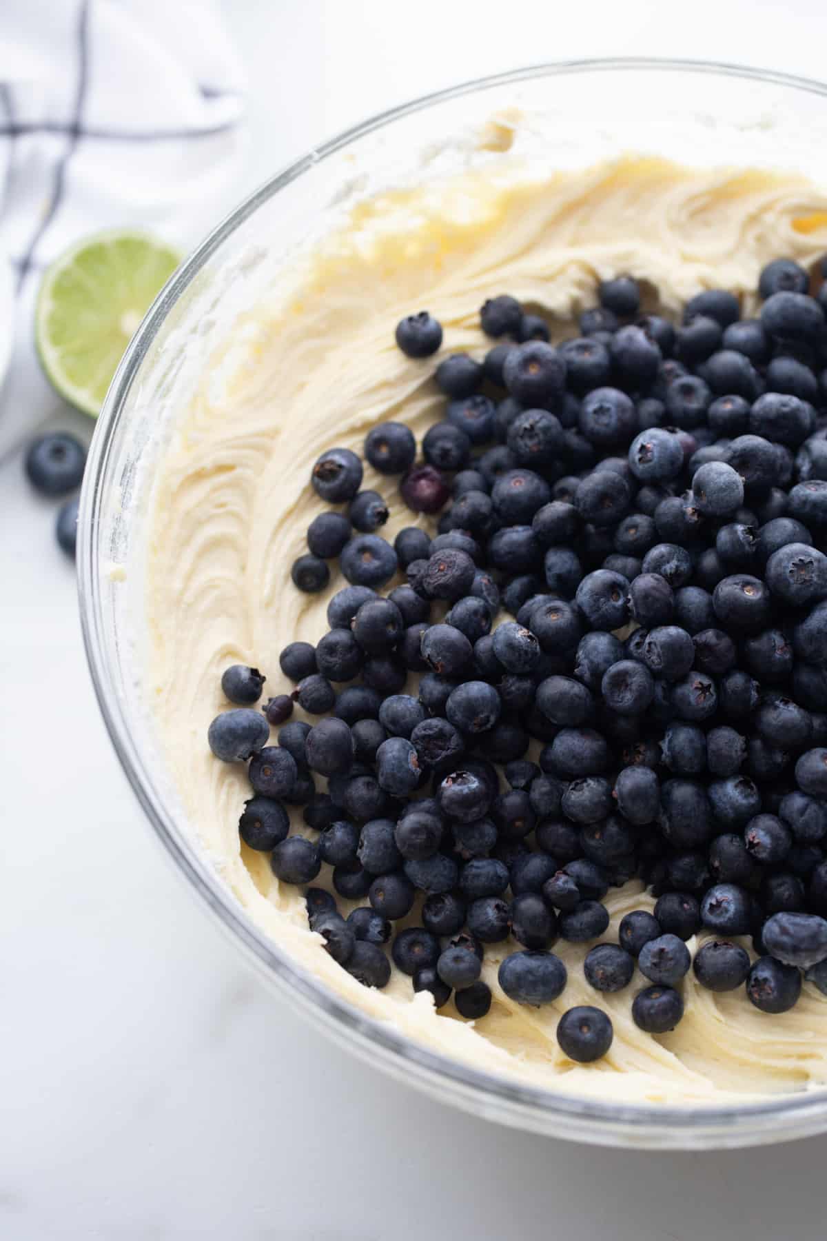 Bowl of batter with fresh blueberries piled on top, just before folding them in.