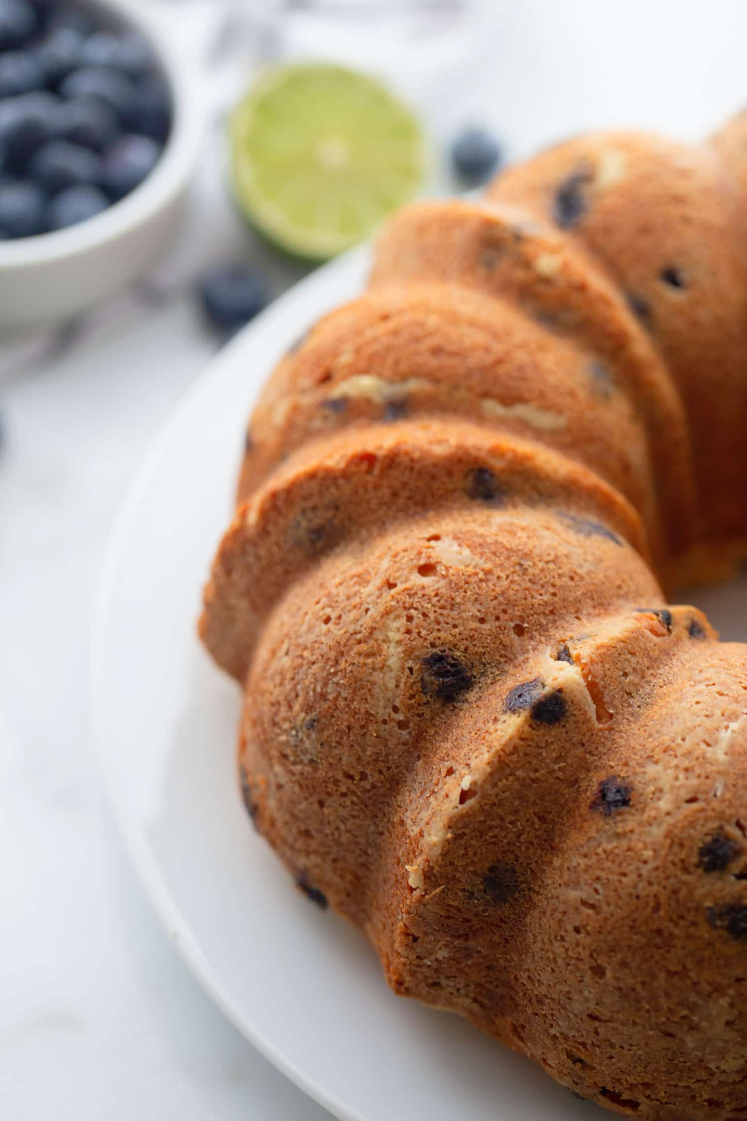 Freshly baked blueberry-lime pound cake cooling on a wire rack, golden brown with no glaze.