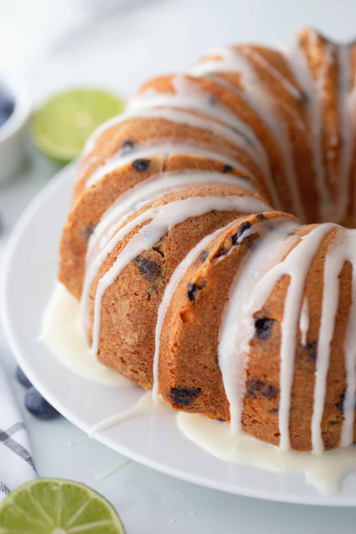 Blueberry-lime pound cake on a plate, fully glazed with lime icing drizzled over the top and sides.