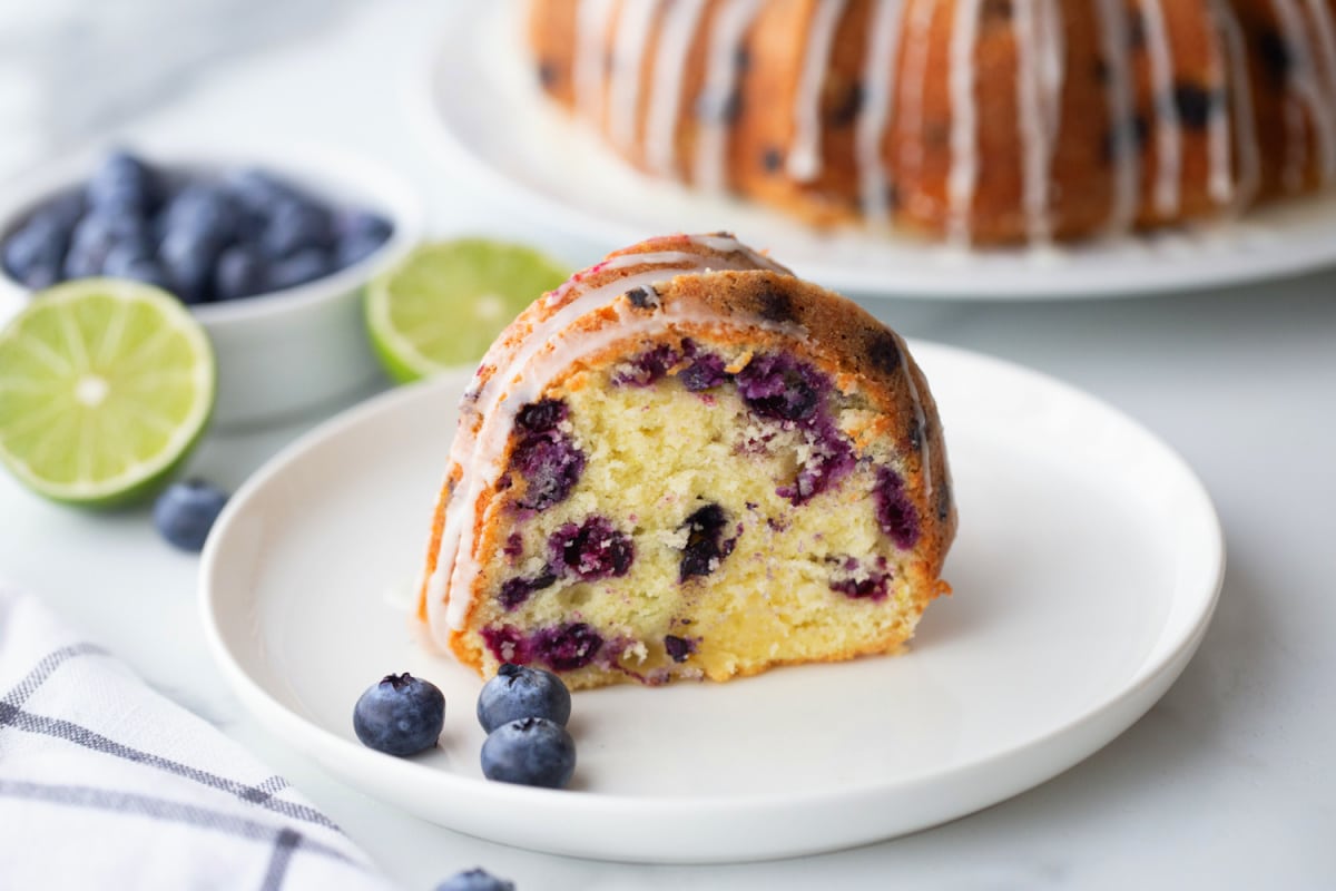 A single slice of blueberry-lime pound cake on a plate, showing the moist interior and blueberry distribution.