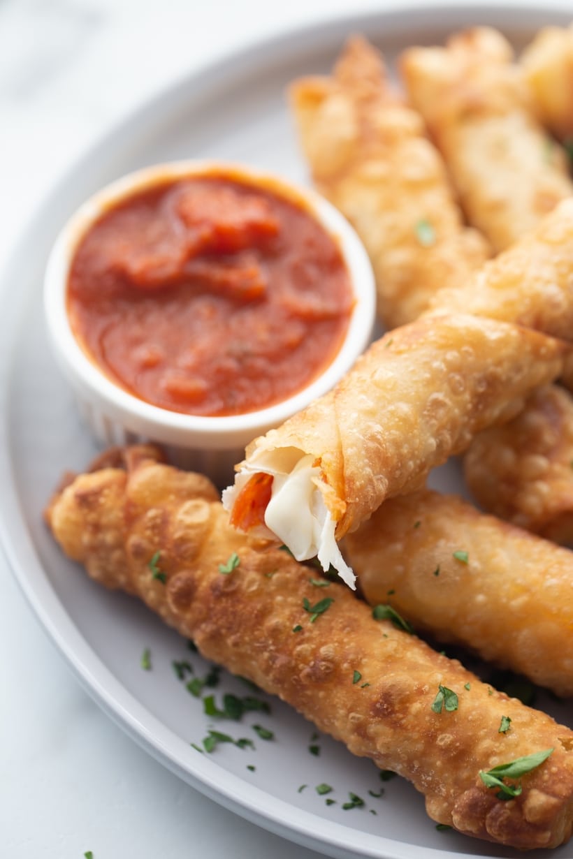 Mozzarella Pepperoni Pizza Sticks made with egg roll wrappers are crunchy on the outside with gooey cheese and pepperoni on the inside. These are a fun appetizer for any party. pizza sticks