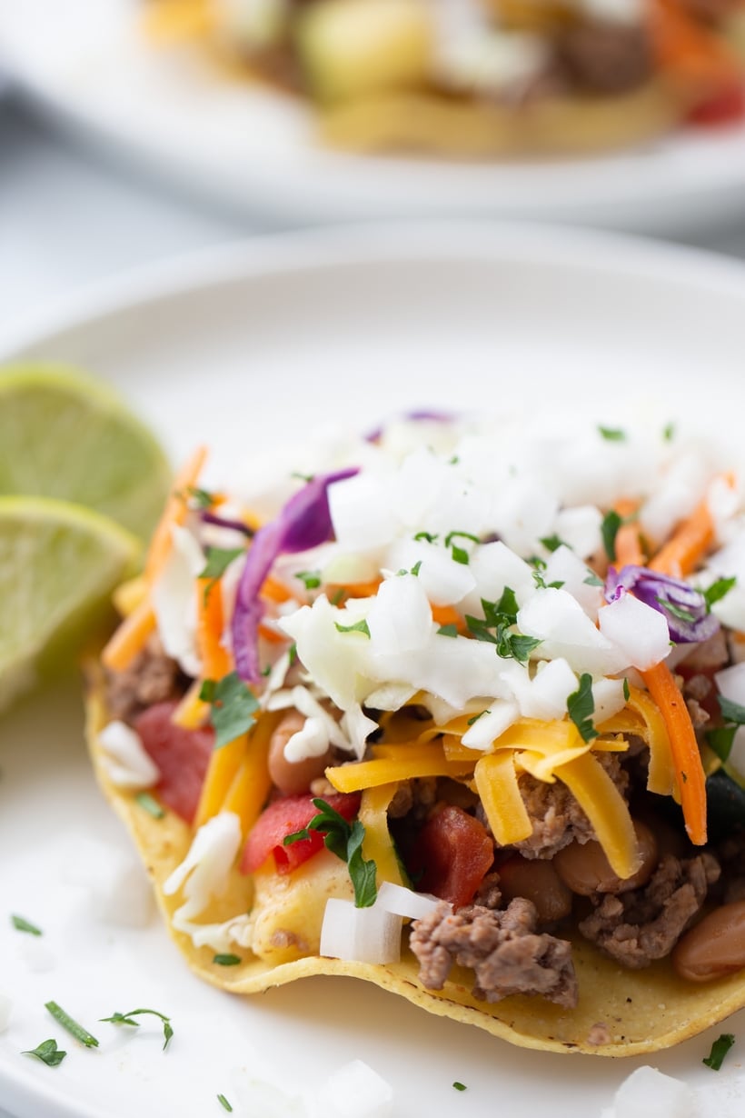 Chipotle Beef Tostada with Full Toppings Close-up of chipotle beef tostada with slaw, cheese, and lime on top