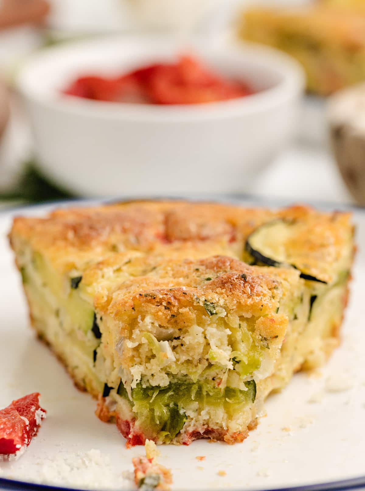 Close-up of a slice of crustless zucchini and red pepper pie with a golden, biscuit-like edge