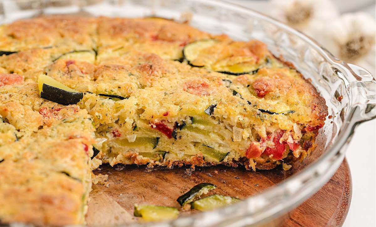 Golden-baked zucchini pie in glass dish showing layers of vegetables and cheese