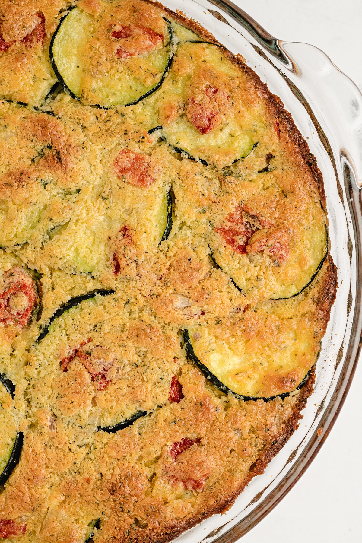 Close-up of golden top crust on zucchini biscuit mix pie with visible slices of squash and red pepper