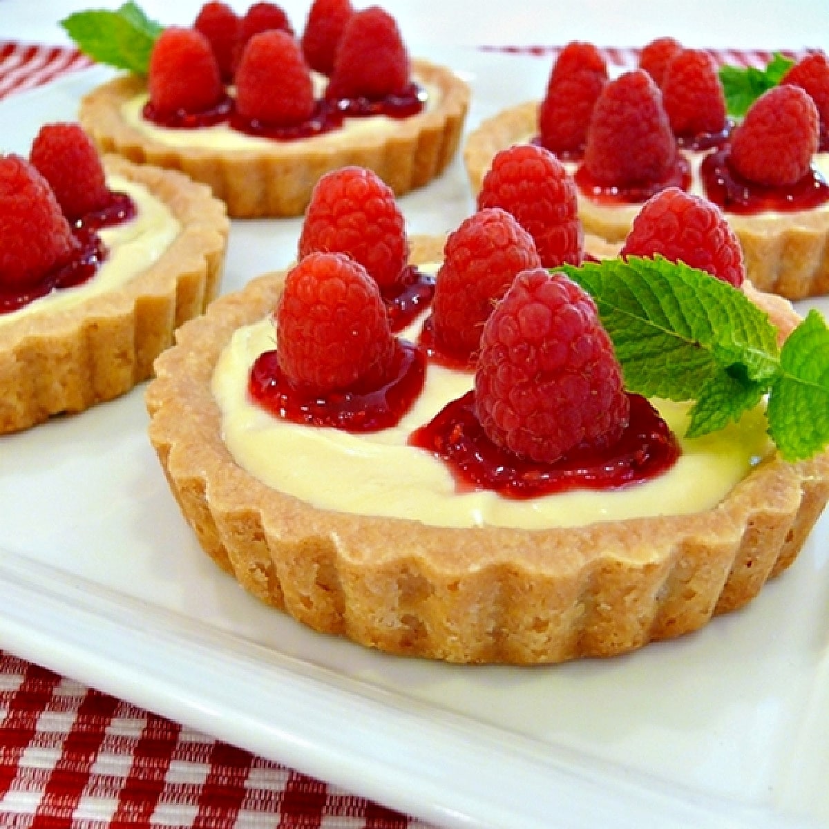 Raspberry lemon tartlets with shortbread crusts, lemon curd cream cheese filling, raspberry jam, and fresh raspberries.