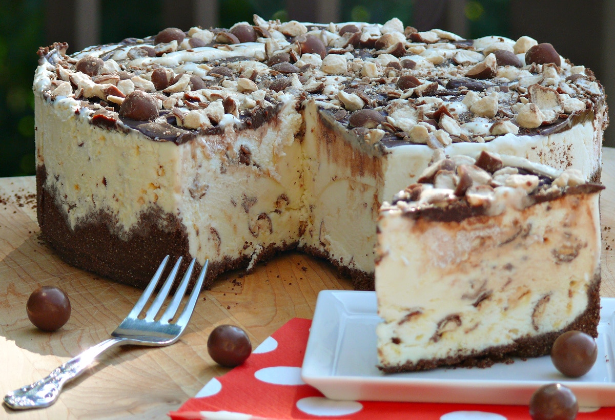 Whoppers Malted Milk Ice Cream Cake with a chocolate graham cracker crust, vanilla malt ice cream filling, chocolate ganache, and crushed malted milk balls. Whole Whoppers Malted Milk Ice Cream Cake topped with chocolate ganache and crushed malted milk balls.