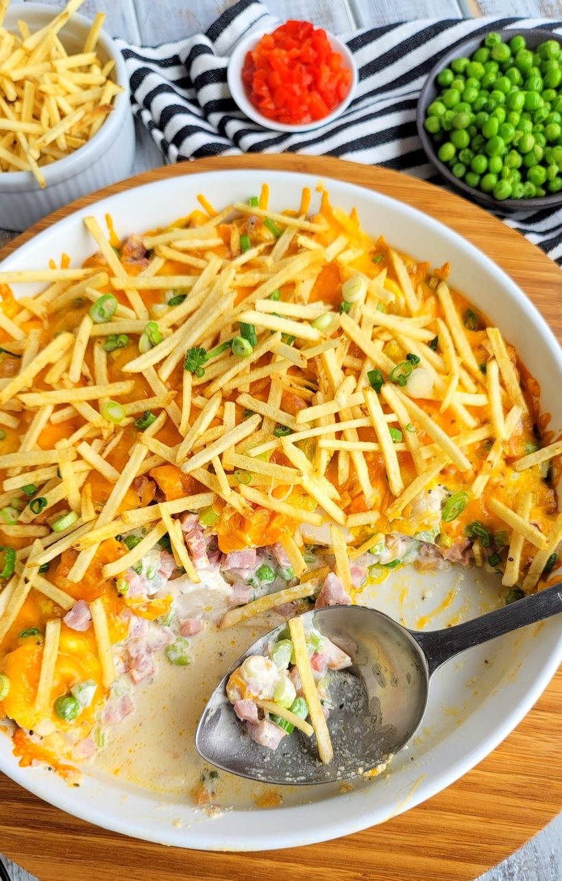Ham and Cheese Casserole with Crunchy Topping being served Top-down shot of the ham and cheese casserole with crunchy topping with a large spoon resting inside and half the casserole served.