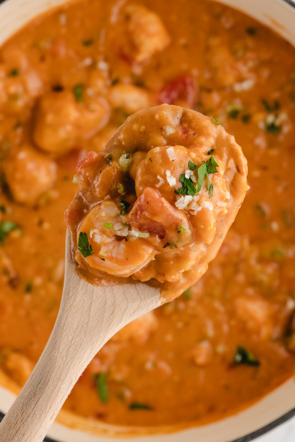 Creamy Shrimp Creole Soup with Bacon-Cornmeal Dumplings in a wooden spoon