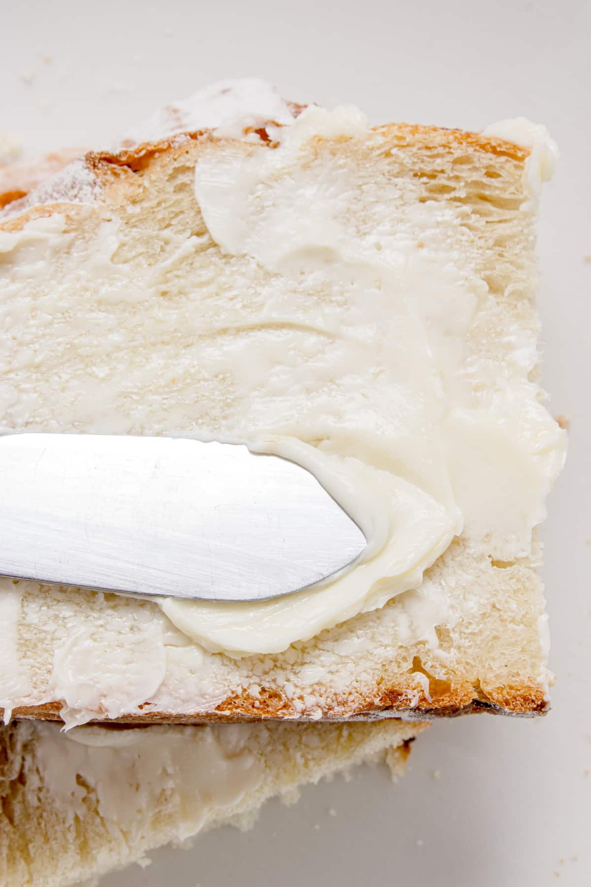 Buttered artisan rosemary bread slice Slice of artisan rosemary bread spread with soft butter showing the airy crumb and crisp crust