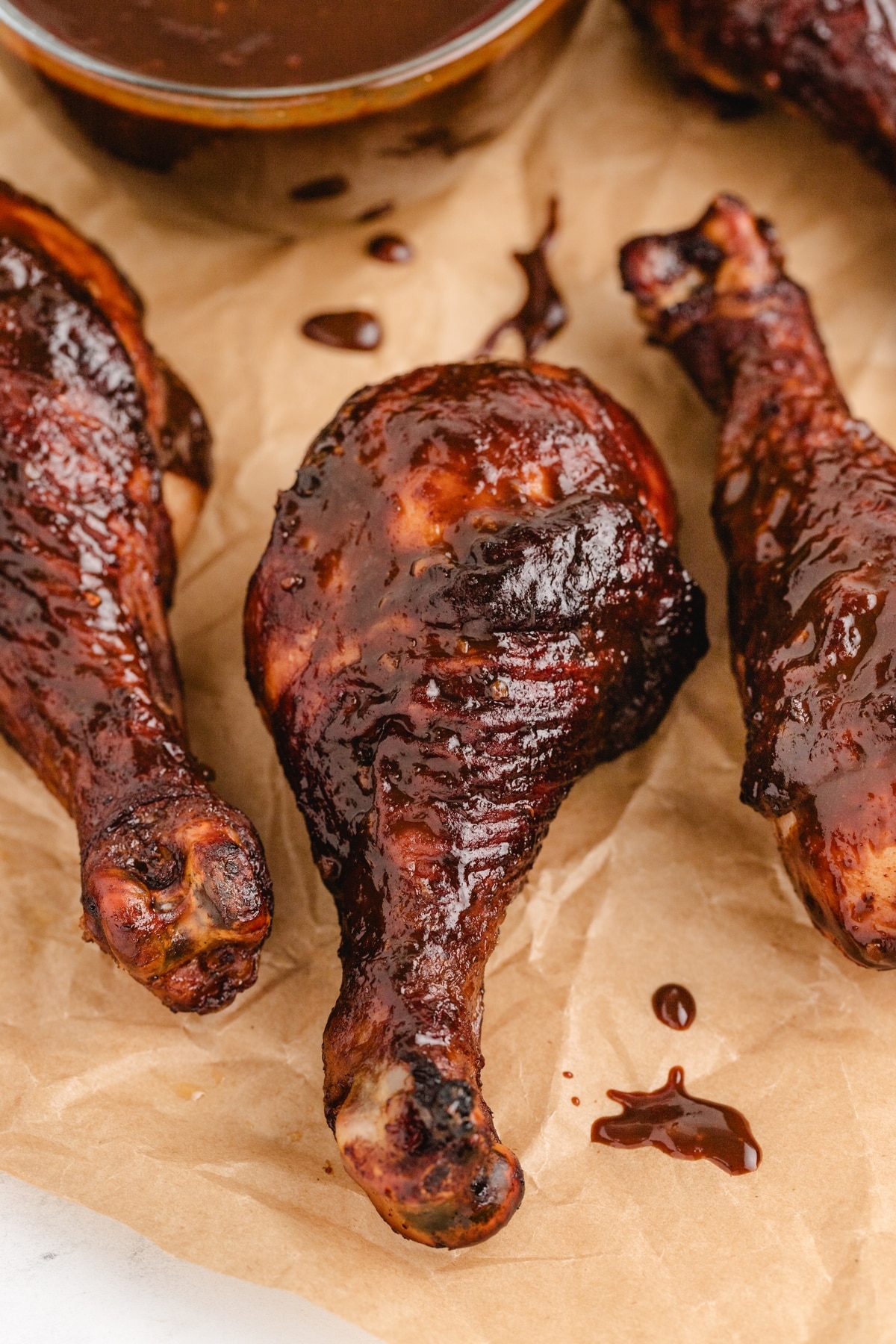 Overhead shot of chicken drumsticks with glaze pooled on parchment