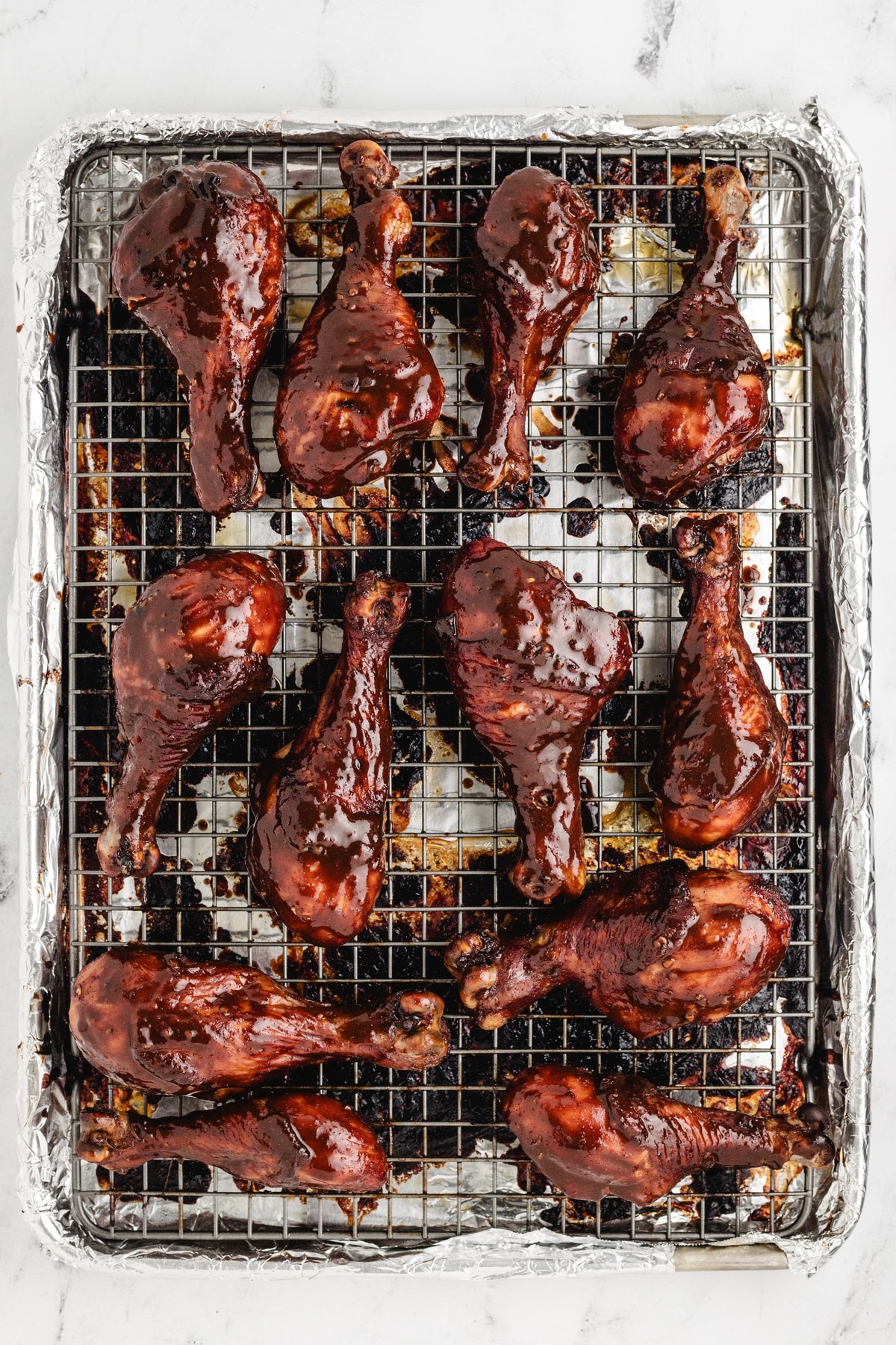 Overhead view of glazed chicken drumsticks on foil-lined rack