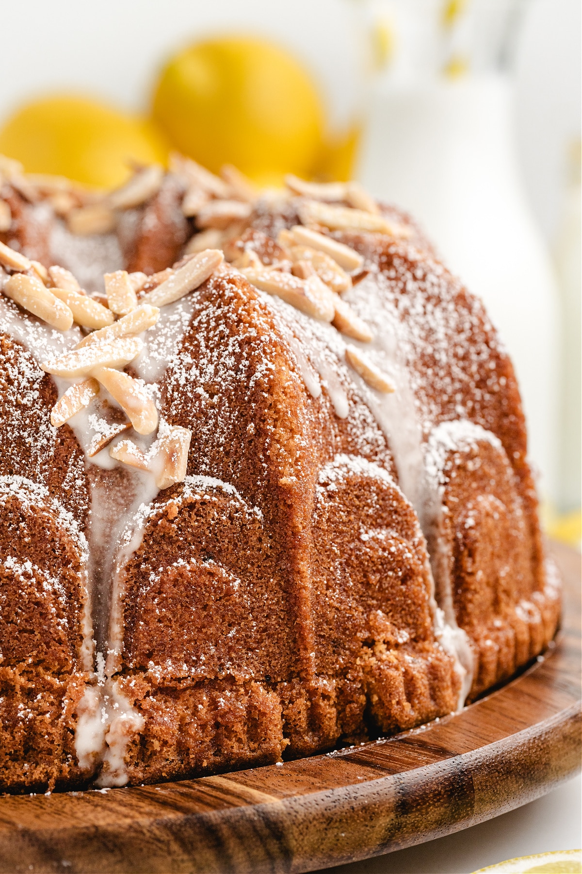 Side View of Limoncello Syrup Lemon Bundt Cake Side view of golden limoncello Bundt cake with lemon glaze and almond crunch