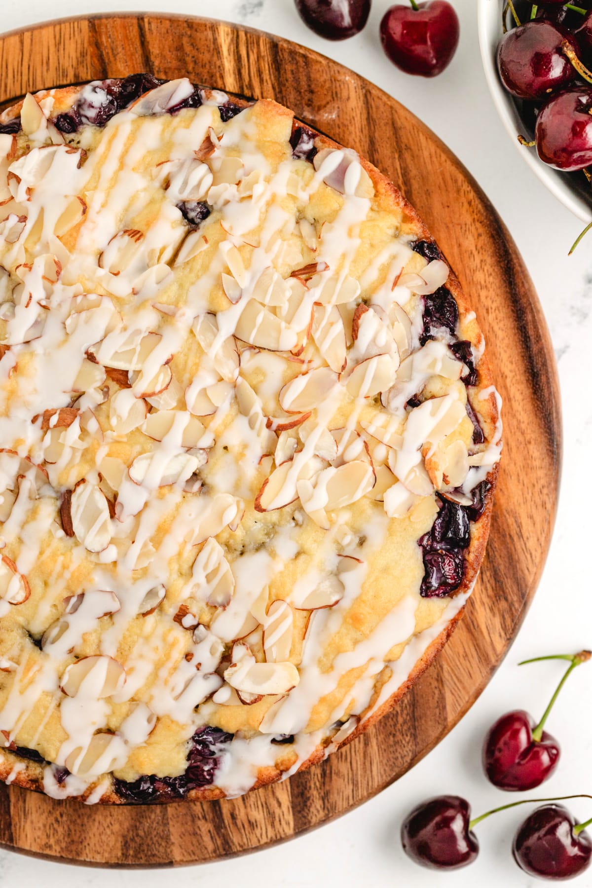 Glazed Cherry Almond Coffee Cake with Fresh Cherry Filling Overhead shot of a full cherry almond coffee cake with glaze and toasted almonds on top