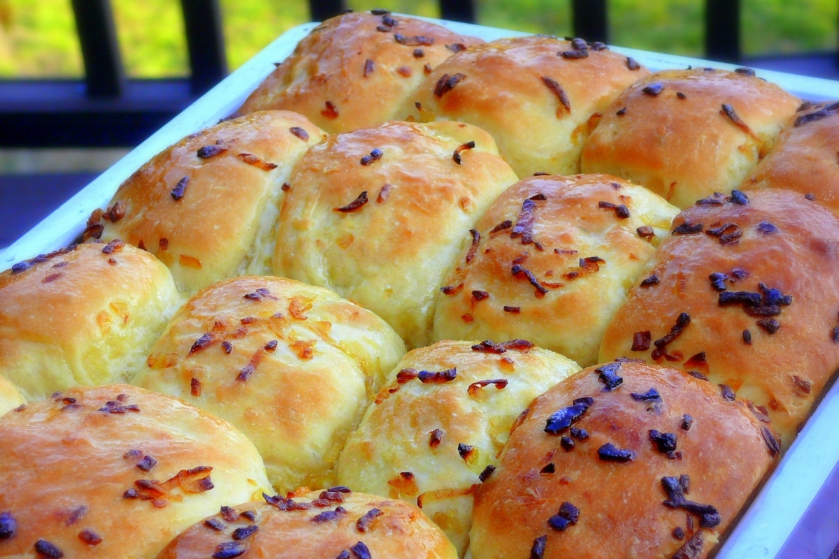 Pan of freshly baked no-knead onion rolls. A pan filled with freshly baked, golden-brown no-knead onion rolls.