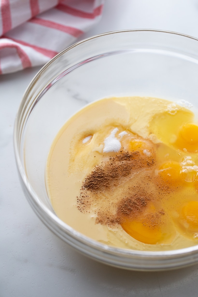 Eggnog mixture in a clear bowl, ready to be poured over the panettone.