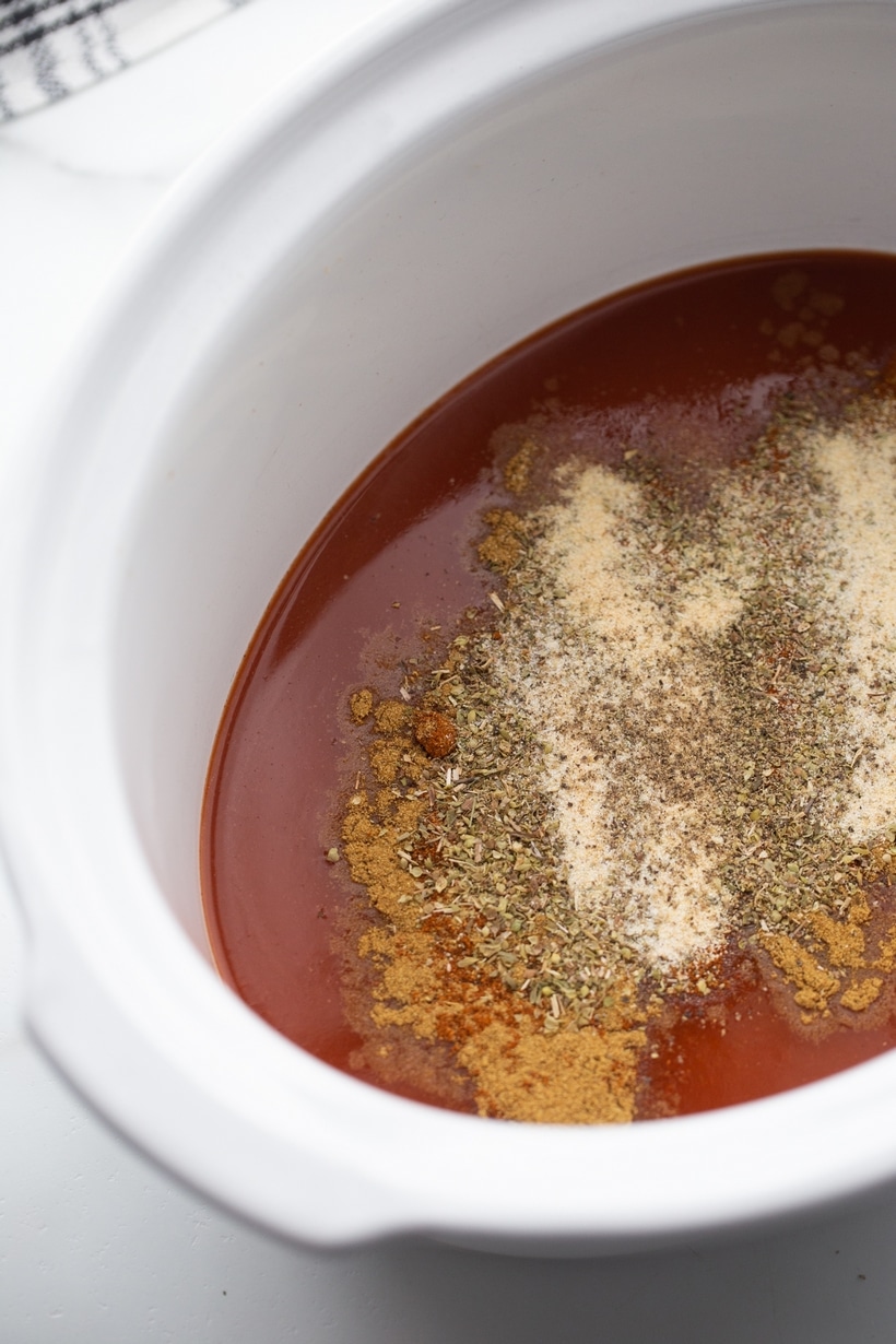 Slow cooker full of Las Palmas red Chile Sauce and seasonings for Chile Colorado beef recipe