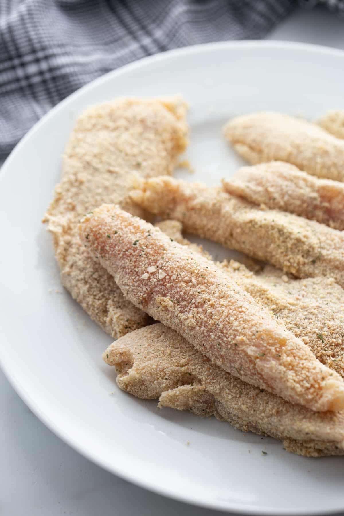 Breaded chicken tenderloins before frying Raw chicken tenderloins coated in seasoned breadcrumbs, ready for the pan