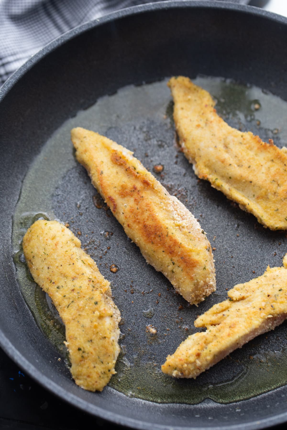 Pan-frying chicken tenderloins Chicken tenderloins frying in a skillet until golden and crisp