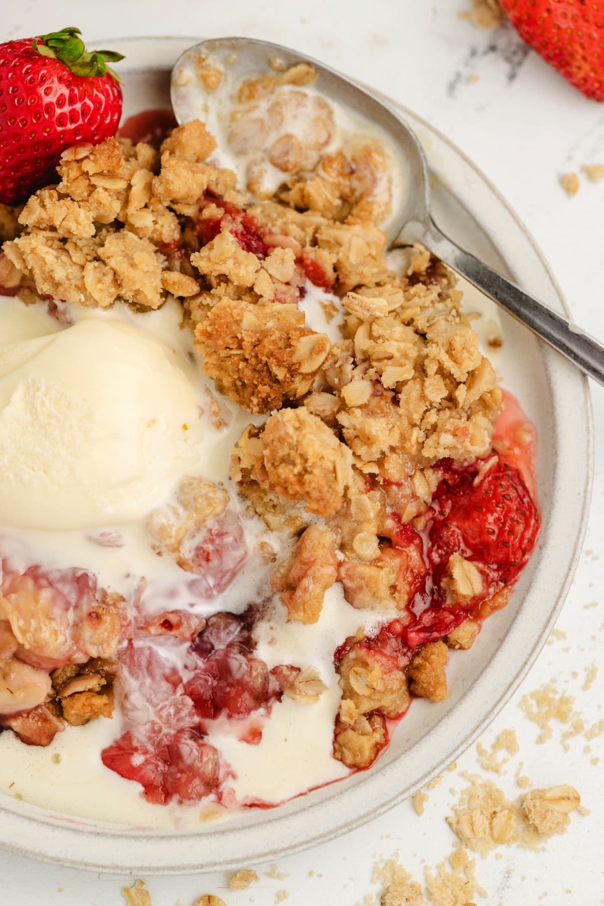 Easy strawberry and banana dessert in serving bowl A bowl of strawberry and banana crumble topped with vanilla ice cream, ready to eat.