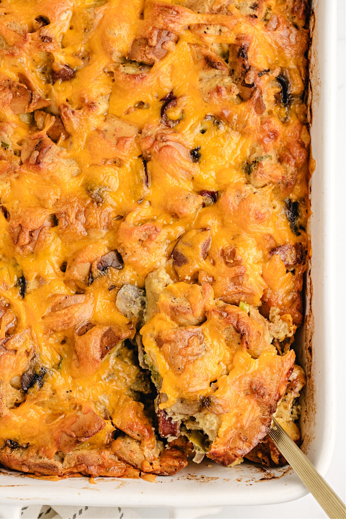 Golden cheesy breakfast casserole in a white baking dish with kielbasa.