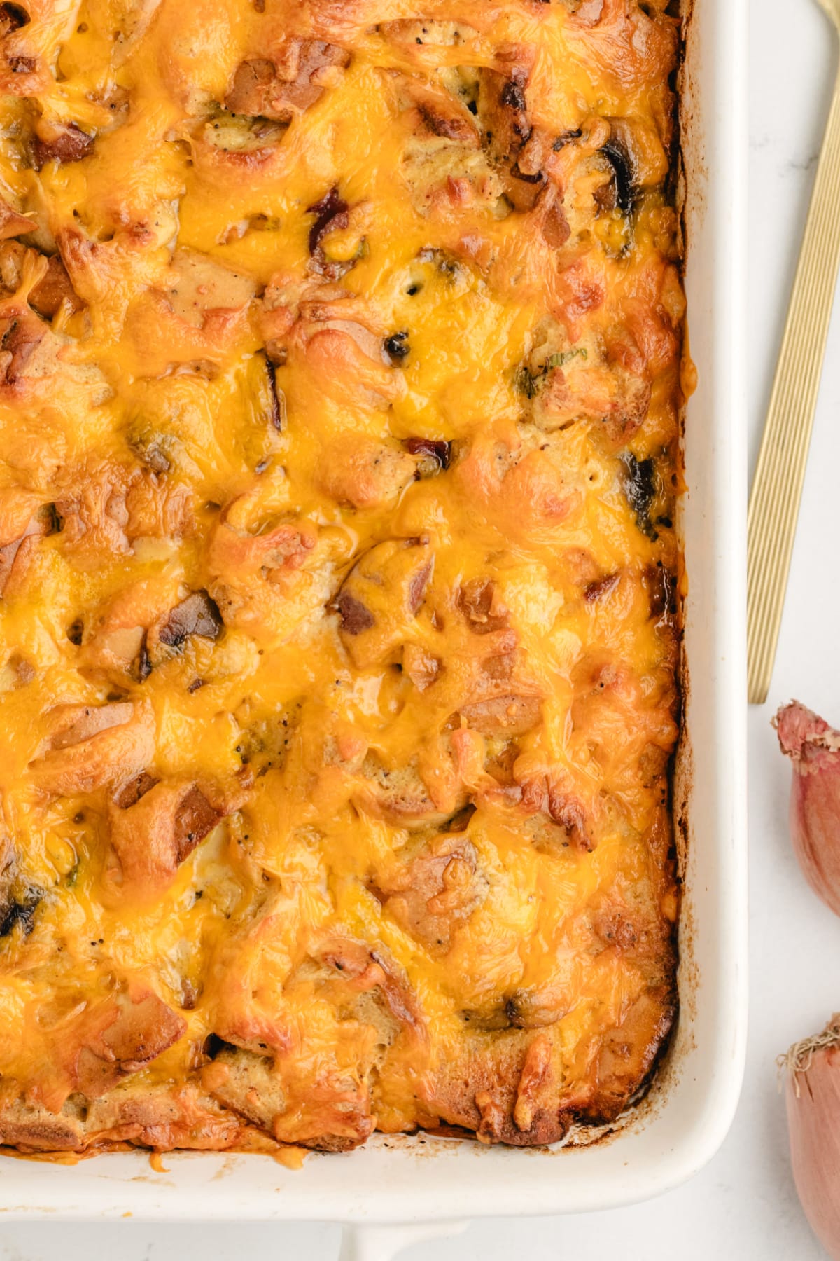 Closeup of overnight breakfast casserole with bagels, kielbasa, and melted cheddar.