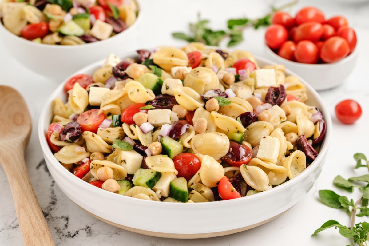 Greek Pasta Salad in a bowl A close-up of the pasta salad, showing the textures of feta, chickpeas, and fresh veggies coated in dressing.