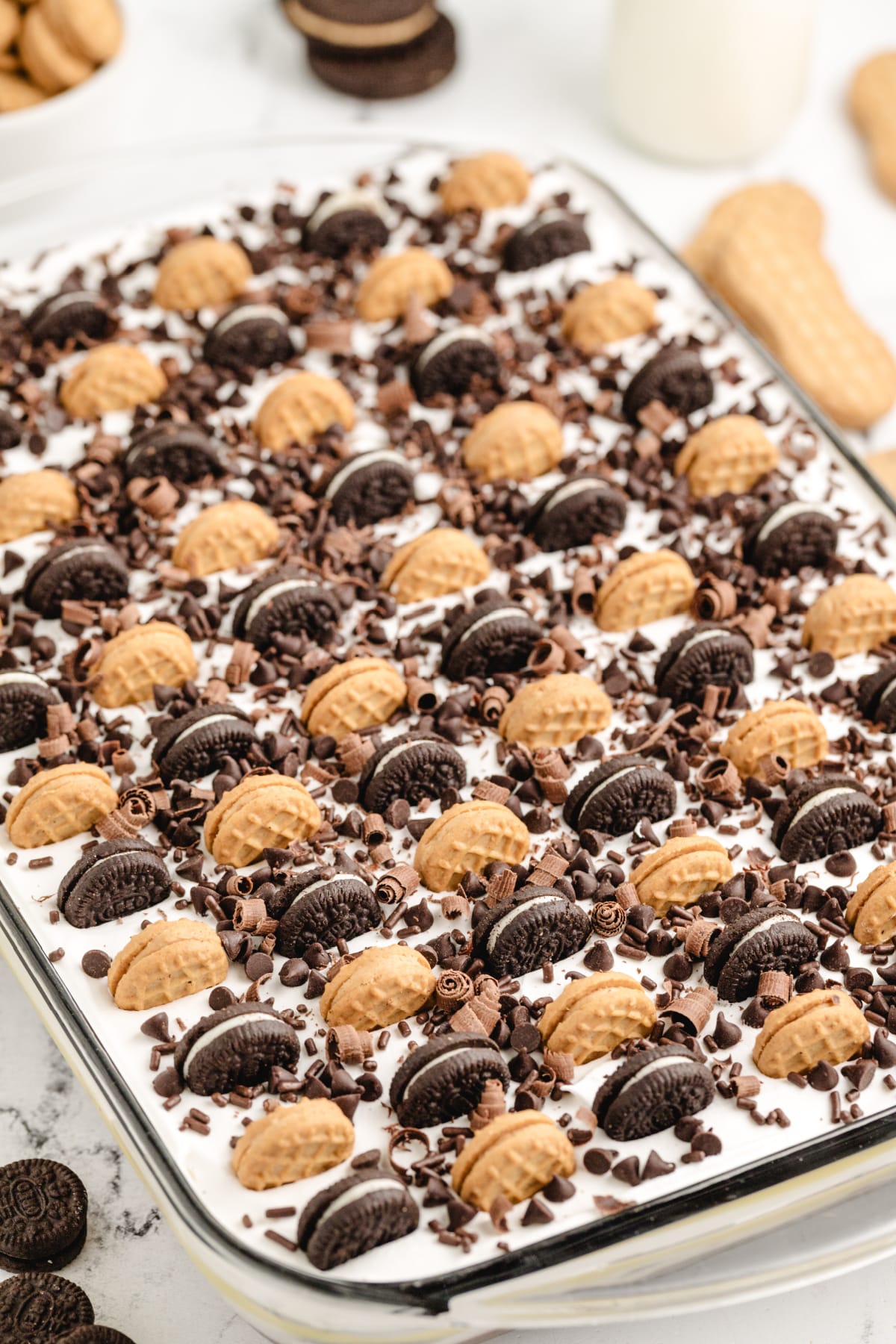 No-bake peanut butter Oreo cake topped with Nutter Butter Bites and chocolate curls Topped peanut butter chocolate icebox cake with mini cookies, sprinkles, and chocolate shavings