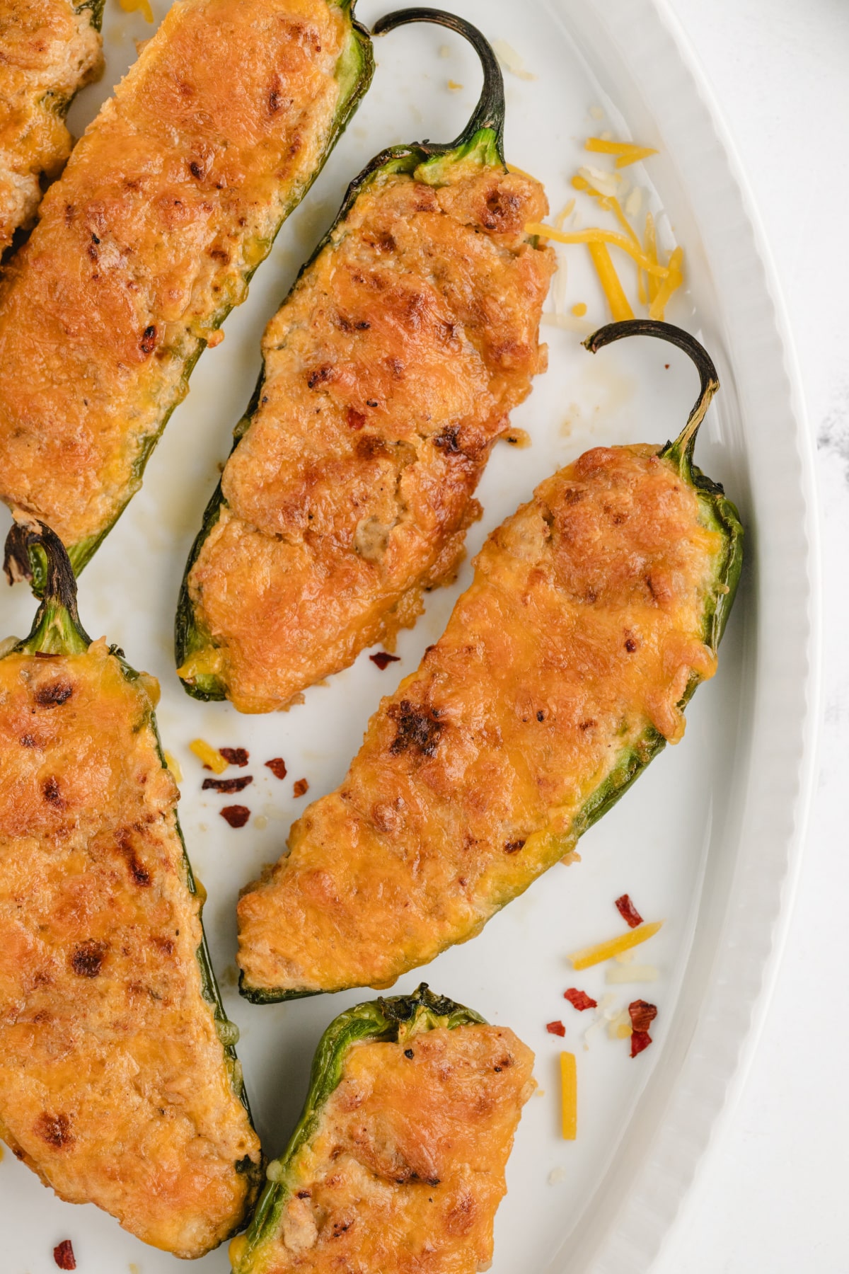 Ground Turkey Stuffed Jalapenos on a plate Close-up of baked ground turkey stuffed jalapeños on a baking sheet, topped with melted cheese and golden edges.