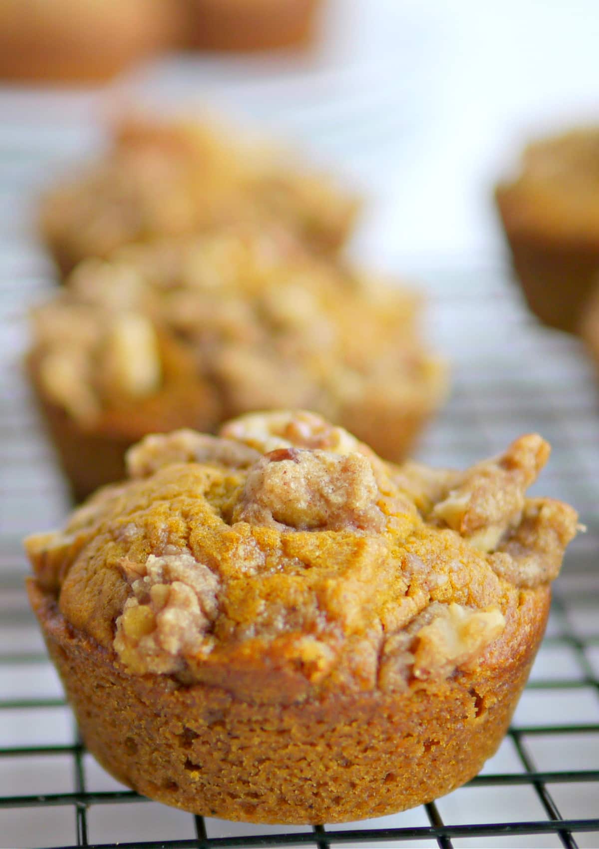 Pumpkin brown sugar muffins with walnut crumble cooling on a rack.