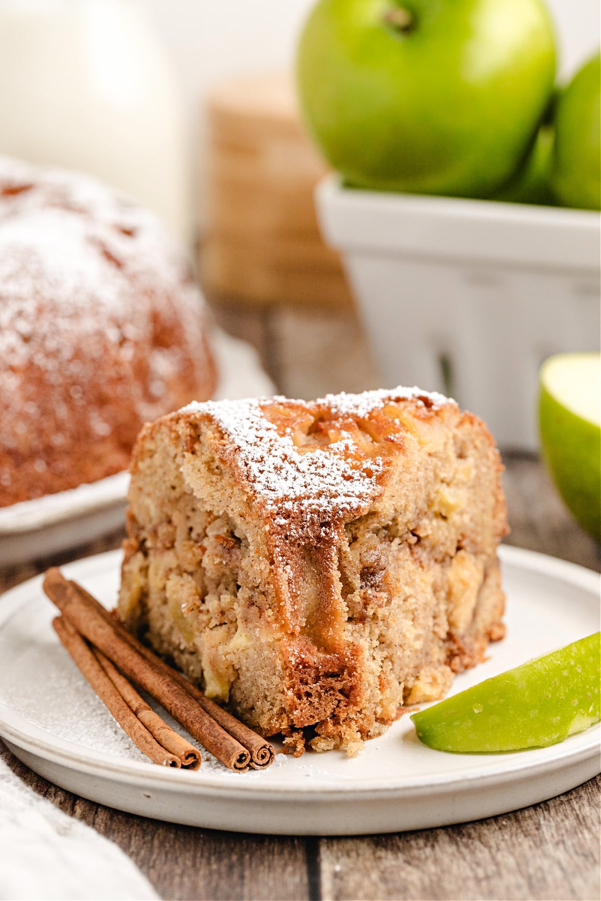 Apple cinnamon bundt cake slice with powdered sugar and a fork ready to eat