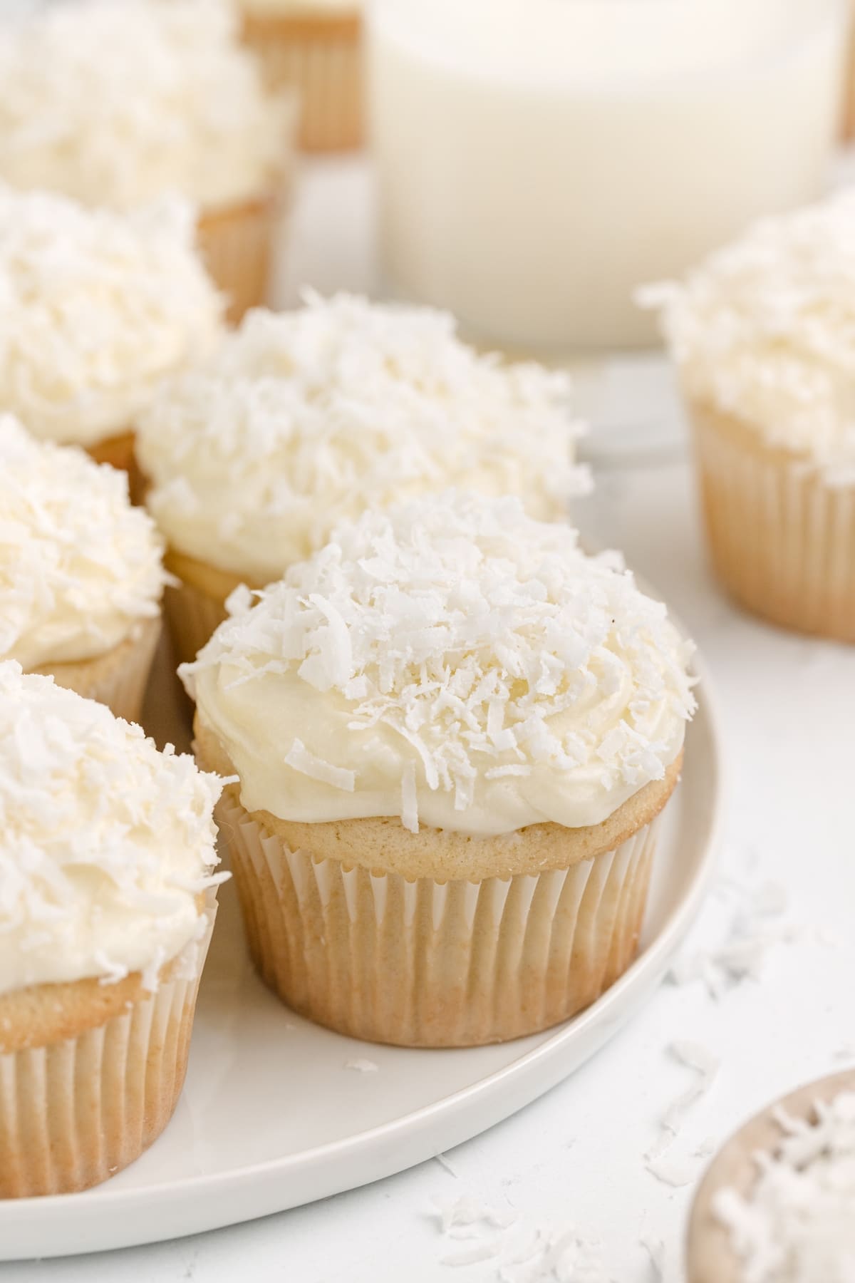 Coconut Cupcakes with Coconut Cream Cheese Frosting on a plate Close-up of a coconut cupcake topped with coconut cream cheese frosting, showcasing the coconut flakes on top.