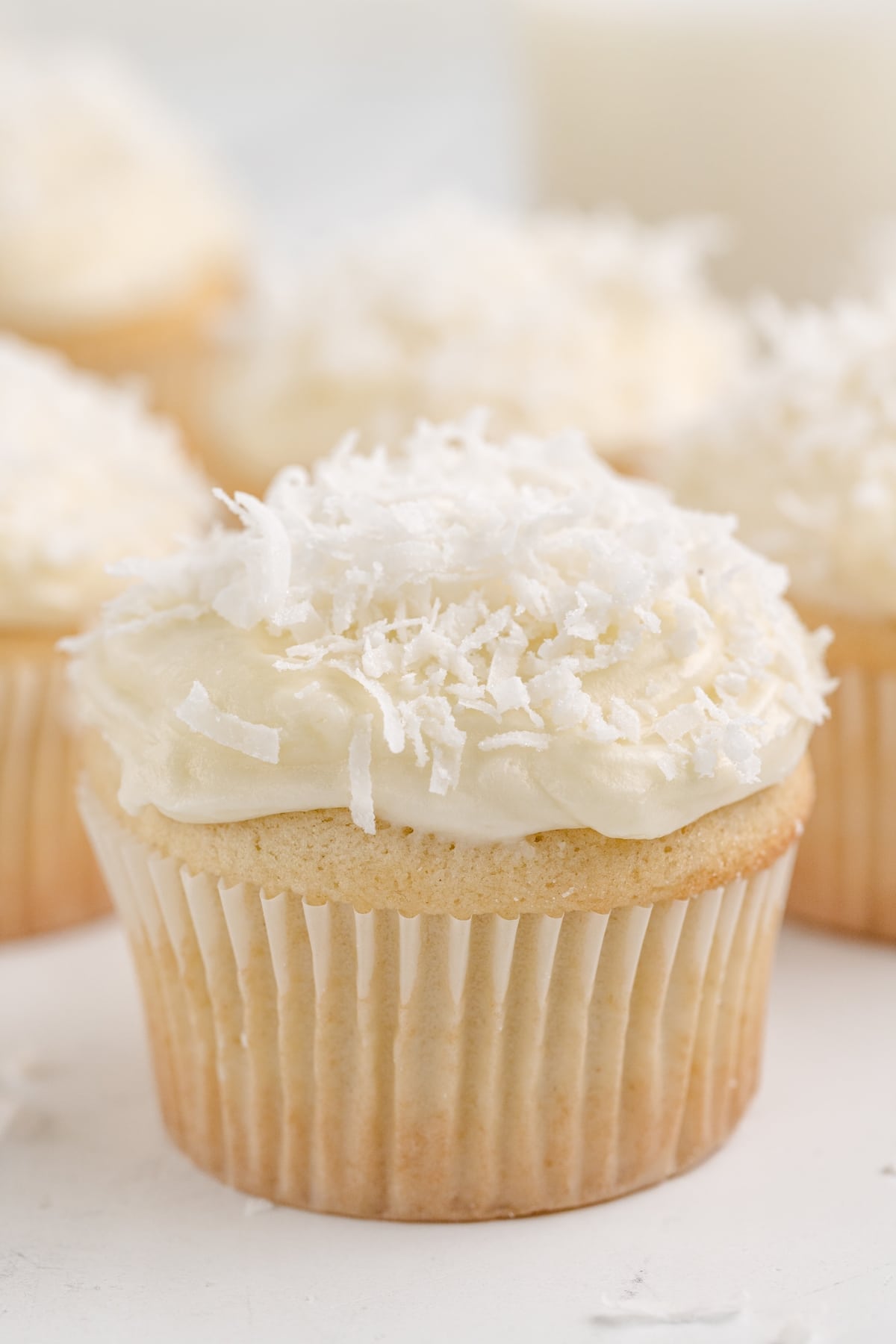 Coconut Cupcakes with Coconut Cream Cheese Frosting in a cupcake liner Coconut cupcakes with a soft, moist texture and a coconut cream cheese frosting swirl, garnished with coconut flakes.