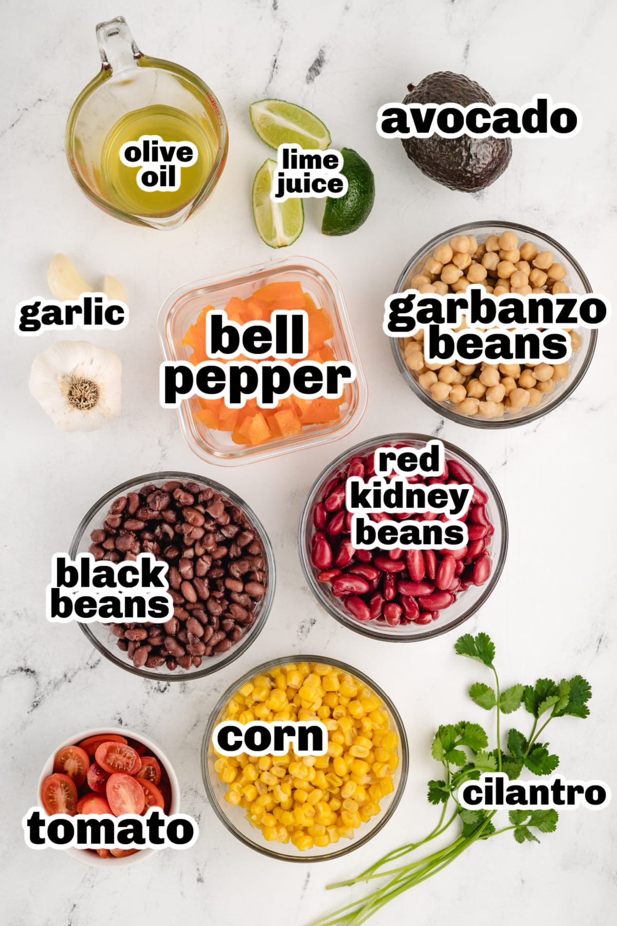 Ingredients laid out before preparation, including canned beans, corn, bell pepper, tomatoes, avocados, cilantro, limes, olive oil, salt, pepper, and garlic.