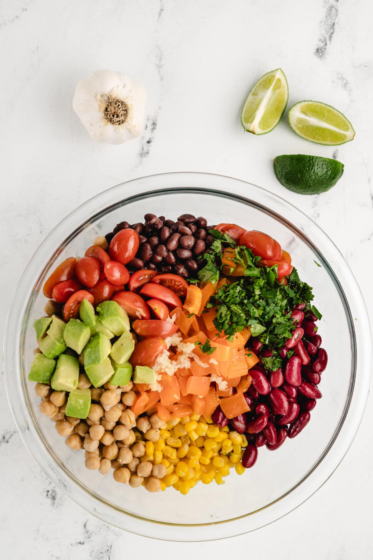 All ingredients in a bowl before mixing, showing the vibrant colors of the chopped vegetables and beans before they are tossed together.
