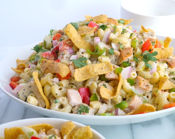 This Kicked-Up Chicken-Macaroni Salad recipe will impress your family and friends at your next picnic, BBQ or tailgate. This chicken macaroni salad pairs well with almost anything and will have your guests begging for more. Kicked-Up Chicken-Macaroni Salad in a white bowl.