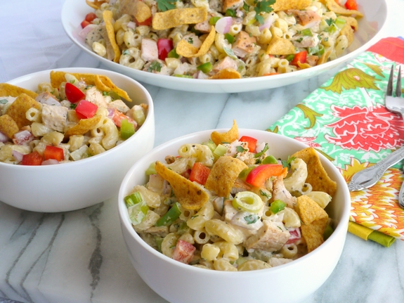 This Kicked-Up Chicken-Macaroni Salad recipe will impress your family and friends at your next picnic, BBQ or tailgate. This chicken macaroni salad pairs well with almost anything and will have your guests begging for more. Kicked-Up Chicken-Macaroni Salad in three bowls with a colorful napkin.