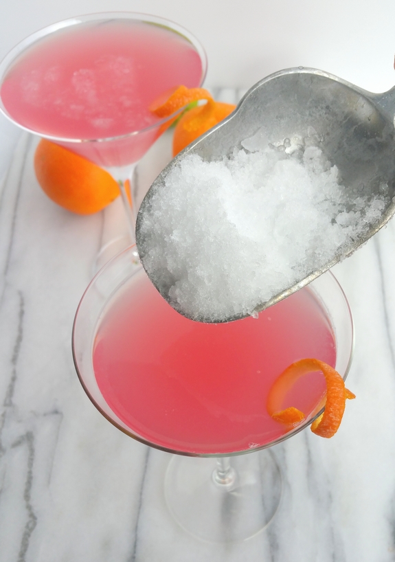 Why would you want to drink anything other than the World's Best Cosmopolitan Cocktail? The only thing girly about this cosmo drink is its color. Two World's Best Cosmopolitan Cocktails with ice being scooped into them.
