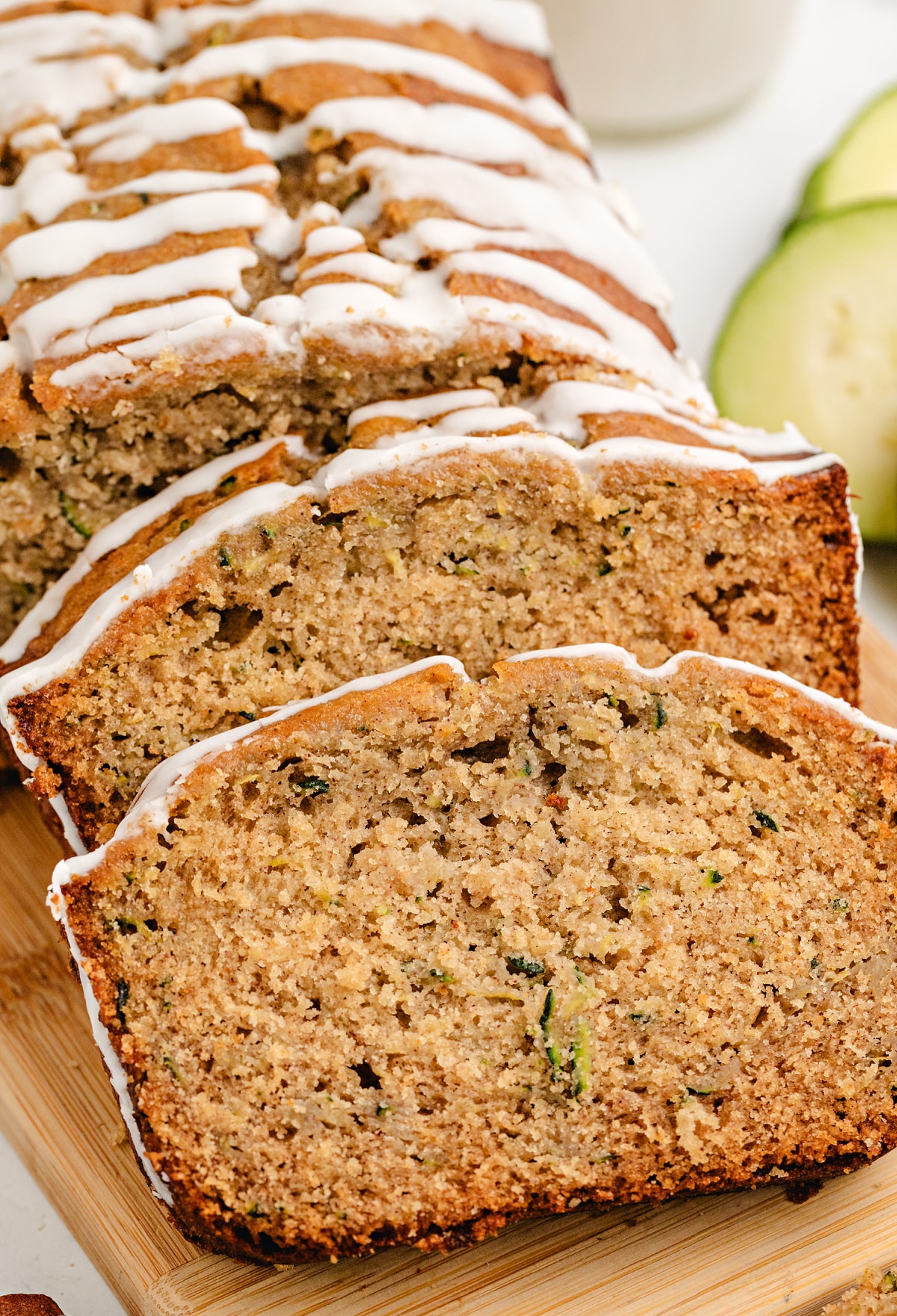Sliced honey zucchini bread on a cutting board with glaze and visible zucchini flecks