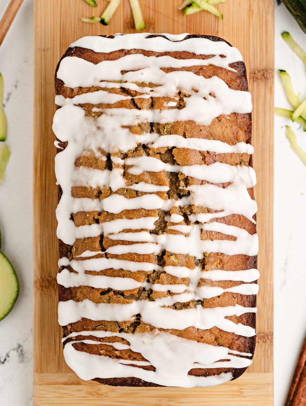 Overhead view of zucchini bread with honey and glaze, cooling on a wooden board