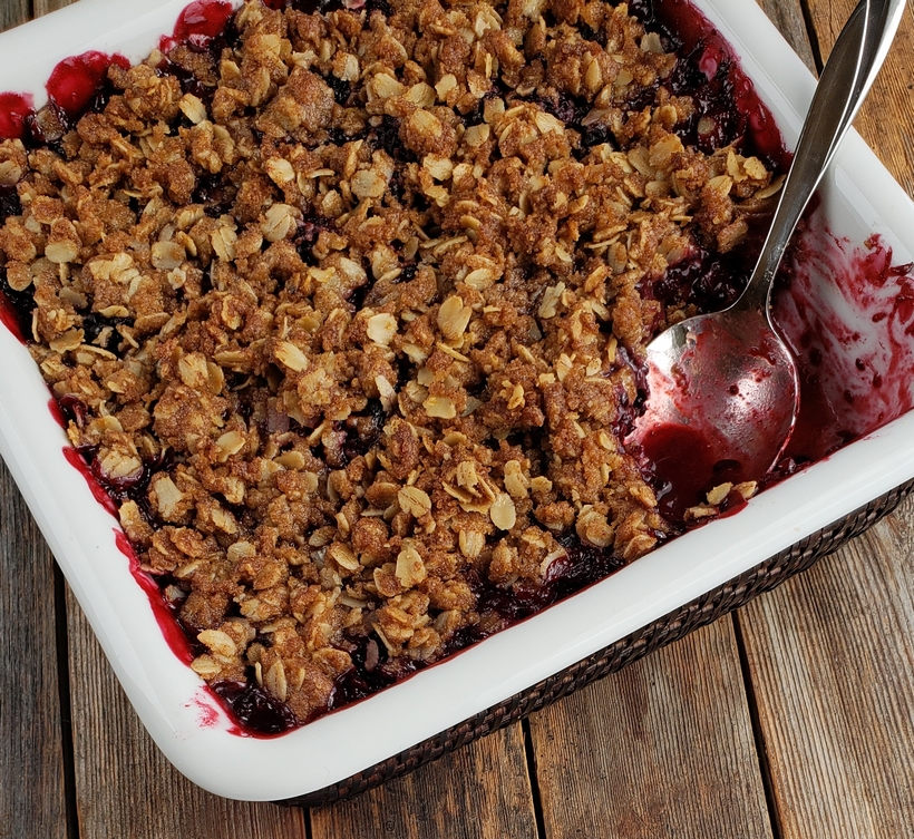 Nothing tastes more like late summer than a Blackberry Crumble. Even if you've never baked from scratch, you will find this recipe so easy to put together. #noblepig #blackberry #crumble #summerdessert Baked Blackberry Crumble with a spoon in a serving dish.