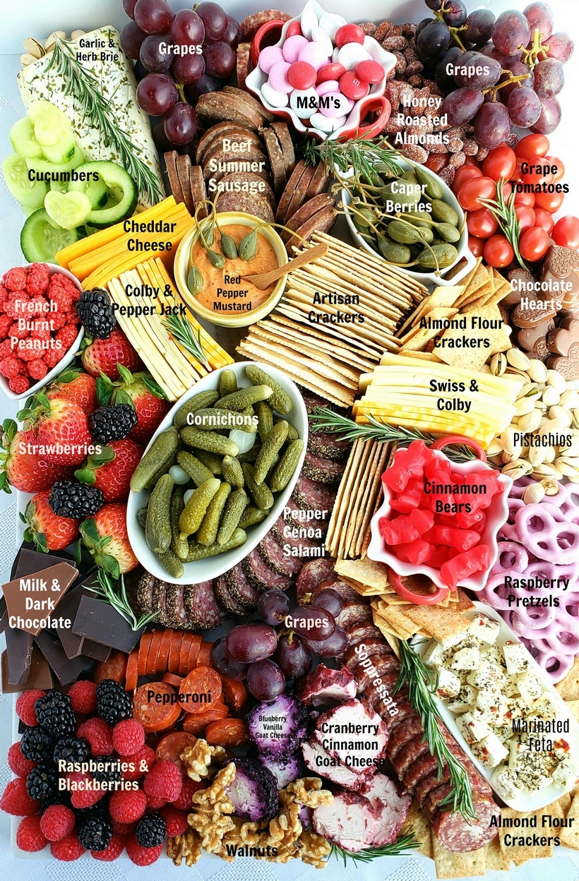 Valentine's Day Charcuterie Board ingredients. The full charcuterie board ingredients styled for serving, with layers of meats, cheeses, crackers, fresh fruit, nuts, and chocolates, set on a table with a festive Valentine’s Day theme.
