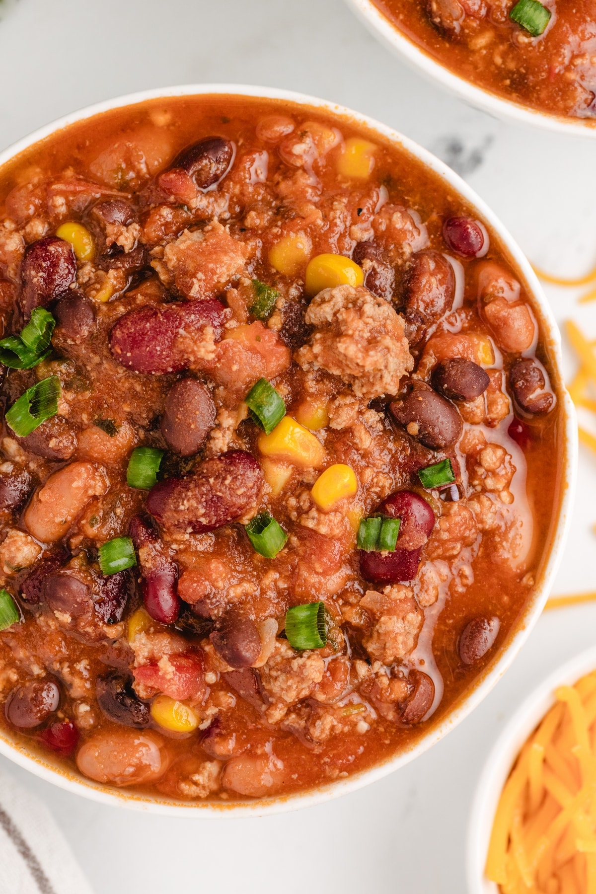 Low Fat Chili Bowl Overhead shot of low fat chili with three kinds of beans, corn, and ground turkey in a white bowl.