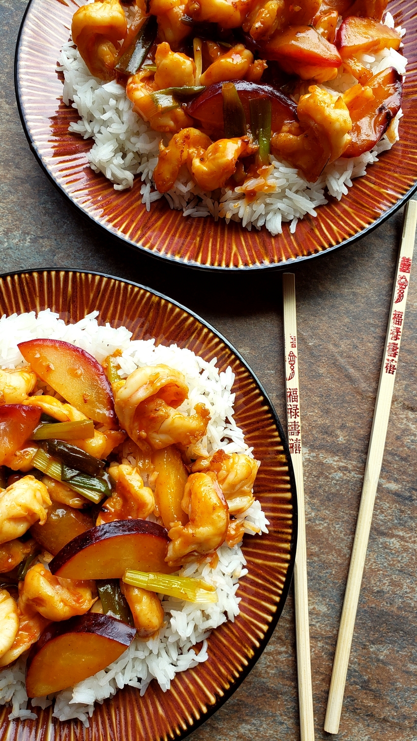 two plates of shrimp stir-fry on top of white rice with chopticks.