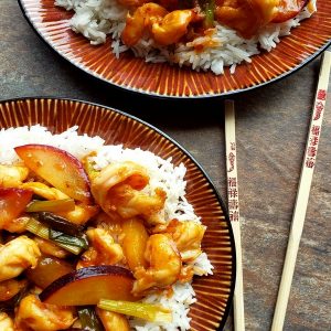 Easy Shrimp and Fresh Plum Stir-Fry over rice with chopsticks on two different plates.
