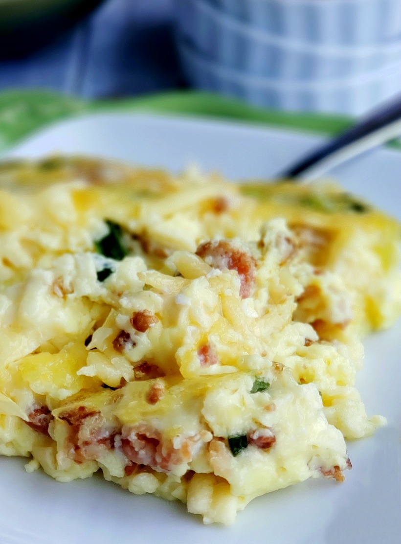 A decadent and sumptuous brunch recipe, this Mouthwatering Oven Omelet will have you wondering why you make eggs any other way. Everyone at your breakfast table will imagine you fussed over this easy omelet, when in reality this egg dish takes very little time to put together. #noblepig #ovenomeletterecipe #ovenomelet #breakfastcasserole #brunchrecipe #bakedomelette #bakedomelet #bruncheggs #bruncheggsforacrowd #bruncheggideas #breakfastfordinner #bruncheggscasserole #brunchideas Serving of omelet on a white plate.