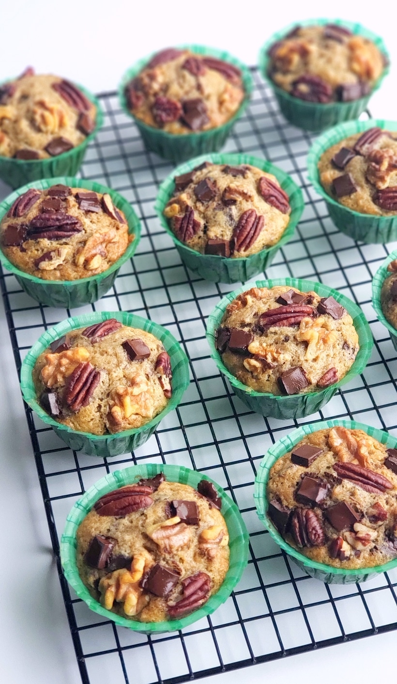 These Eggnog Banana Bread Muffins are tender, delicious and full of pure banana flavor. The eggnog lends a gentle nod to the holidays in a format that is perfect for celebrating Christmas brunch. This holiday breakfast muffin is the perfect cure to hunger while unwrapping those holiday gifts. #noblepig #eggnog #eggnogmuffins #eggnogbananamuffins #holidaybreakfastrecipes #holidaybreakfastideas #christmasbrunch #holidaymuffinrecipe #fluffyeggnogmuffins #christmasbreakfast #muffins #muffinrecipe Eggnog Banana Bread Muffins sitting on a cooling tray.