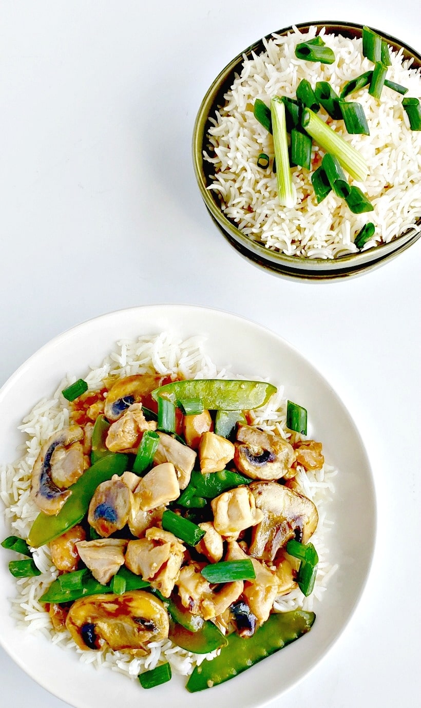 Chicken and snow pea stir-fry on a plate and a bowl of rice.