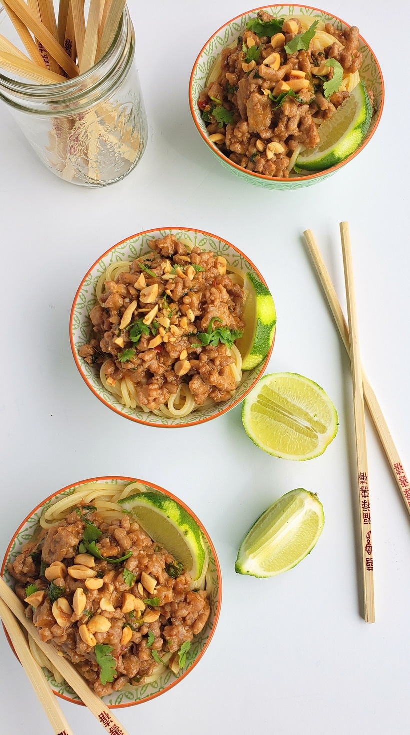 Overhead shot of dan dan pork noodles, three bowls and chopsticks.. 