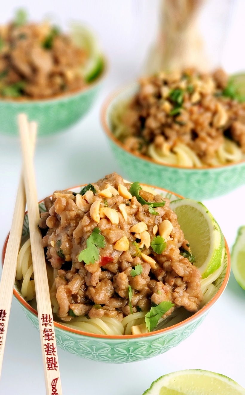 Dan dan noodles in three bowls with chopsticks.